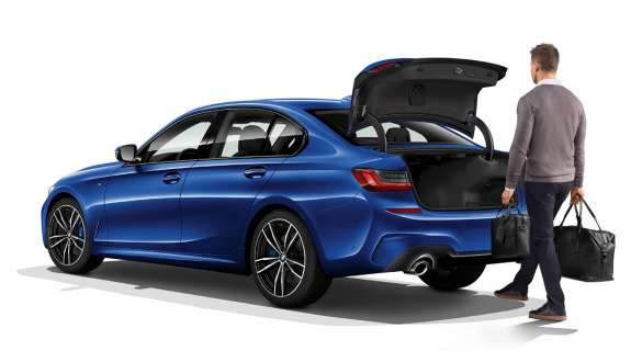 BMW serii 3 Limuzyna (G20), automatyczna obsługa klapy tylnej. Tylny półprofil BMW serii 3 Limuzyna (G20) z kierowcą otwierającym klapę tylną automatycznie stopą.