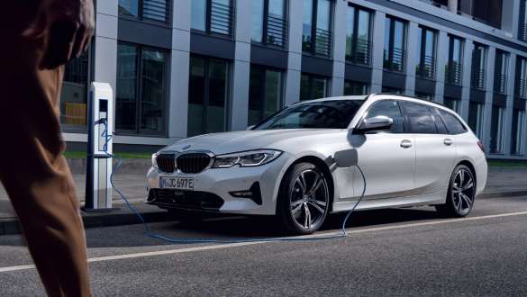 Hybryda plug-in BMW serii 3 Touring 2021 G21, przedni półprofil podczas ładowania Hybryda plug-in BMW serii 3 Touring 2021 G21, przedni półprofil podczas ładowania przed budynkiem