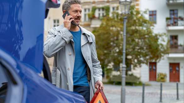 Mężczyzna stojący przy bagażniku BMW serii 5 Limuzyna G30 Mężczyzna stojący przy bagażniku BMW serii 5 Limuzyna G30 z telefonem komórkowym i trójkątem ostrzegawczym w rękach