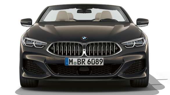 BMW M850i xDrive Cabrio, przód. BMW M850i xDrive Cabrio w metalizowanym kolorze szarego drawitu z otwartym dachem, przód z atrapą chłodnicy w kolorze Cerium Grey.