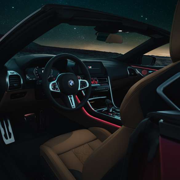 BMW M8 Competition Cabrio, kokpit. BMW M8 Competition Cabrio, kokpit w nocy z kierownicą skórzaną M i czerwonym oświetleniem ambientowym.