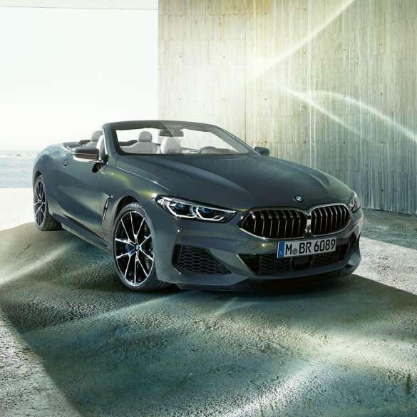 BMW M850i xDrive Cabrio, przedni półprofil. BMW M850i xDrive Cabrio w metalizowanym kolorze szarego drawitu z otwartym dachem, przedni półprofil, stojące przed wybrzeżem.