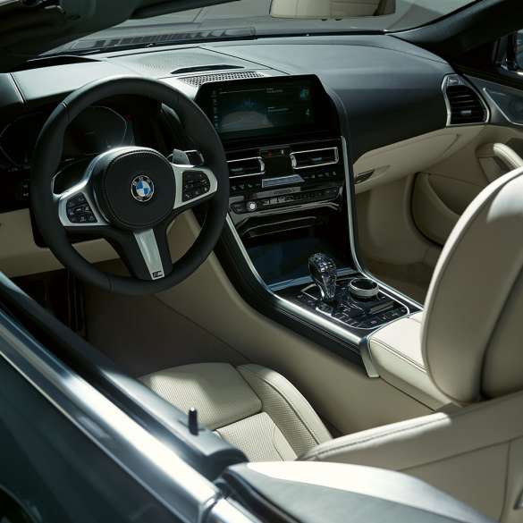 BMW M850i xDrive Cabrio, kokpit. BMW M850i xDrive Cabrio w metalizowanym kolorze szarego drawitu z otwartym dachem, kokpit z kierownicą sportową M.