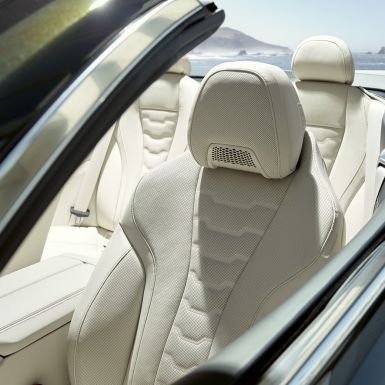W BMW M850i xDrive Cabrio, wielofunkcyjne fotele przednie. BMW M850i xDrive Cabrio w metalizowanym kolorze szarego drawitu z otwartym dachem, wnętrze z fotelami wielofunkcyjnymi obitymi tapicerką BMW Individual ze skóry Merino w kolorze kości słoniowej.
