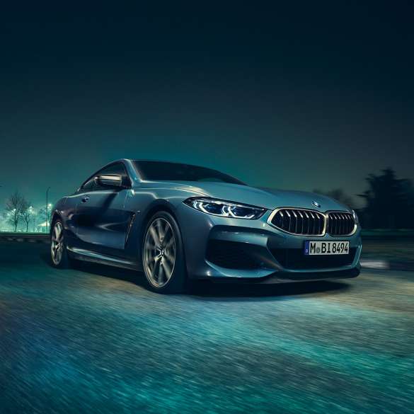 BMW M850i xDrive Coupé, lewy przedni półprofil. BMW M850i xDrive Coupé w metalizowanym kolorze niebieskim Barcelona, lewy przedni półprofil, jadące w nocy.