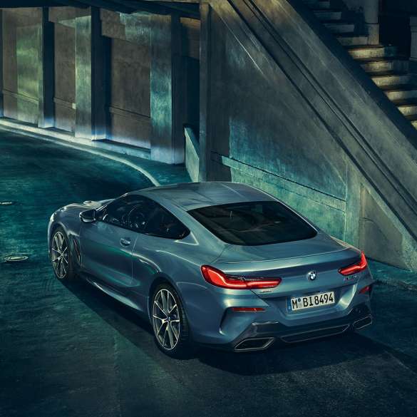 BMW M850i xDrive Coupé, lewy tylny półprofil. BMW M850i xDrive Coupé w metalizowanym kolorze niebieskim Barcelona, lewy tylny półprofil, stojące w nocy.