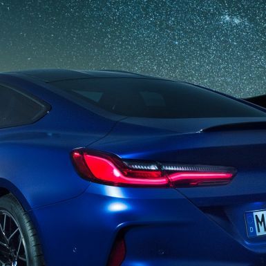 Spojler tylny M BMW M8 Competition Coupé w metalizowanym kolorze niebieskim Marina Bay, nocne ujęcie partii barkowej karoserii ze spojlerem tylnym M z karbonu.