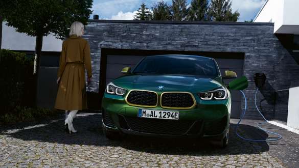 Hybryda plug-in BMW X2 xDrive25e F39 widok z przodu przed garażem Hybryda plug-in BMW X2 xDrive25e F39 widok z przodu przed garażem z modelem