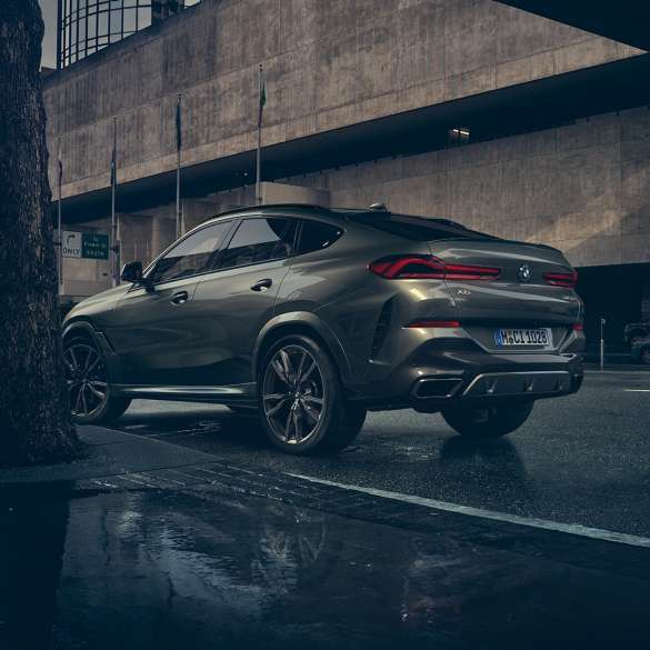 BMW X6, wygląd zewnętrzny. BMW X6, ujęcie w półprofilu od tyłu na tle scenerii miejskiej.