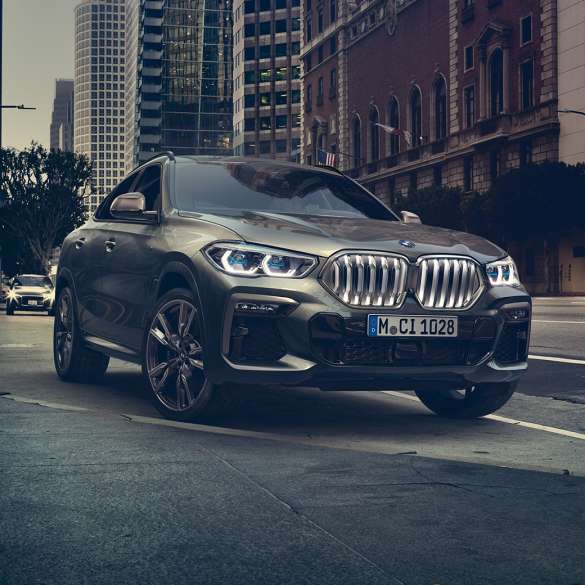 Adaptacyjne zawieszenie BMW X6 M Professional BMW X6, ujęcie w półprofilu od przodu na tle scenerii miejskiej.