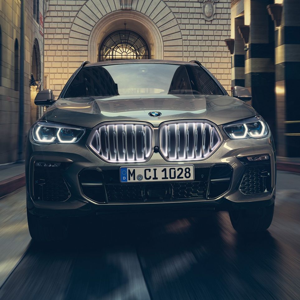 BMW X6 z atrapą chłodnicy BMW z efektem „Iconic Glow”. BMW X6 widoczny od przodu w scenerii miejskiej.