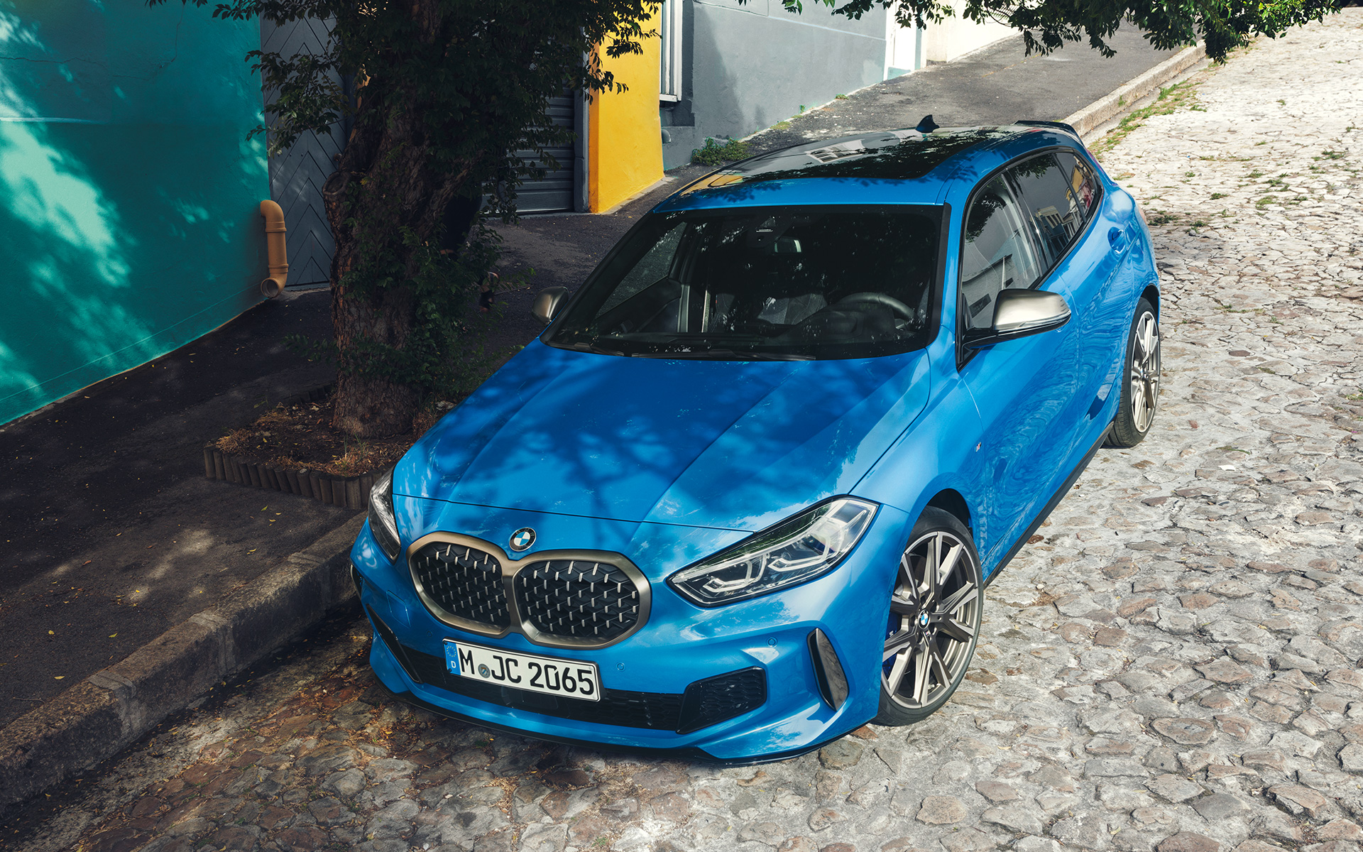 BMW serii 1 M135i F40 na skraju drogi BMW serii 1 M135i F40 w metalizowanym kolorze niebieskim Misano, przedni półprofil podczas postoju na skraju drogi, widok z góry