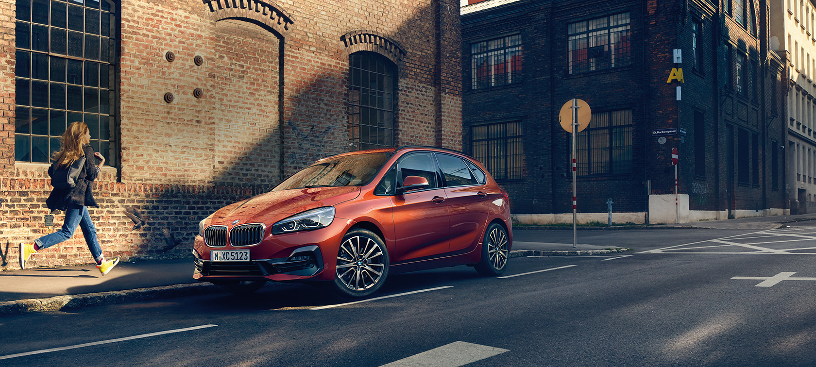 Zaparkowane BMW serii 2 Active Tourer BMW serii 2 Active Tourer F45, modernizacja 2018, pomarańczowy zachód słońca, metalizowany, przedni półprofil parkującego samochodu