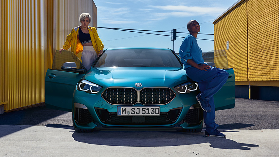BMW serii 2 Gran Coupé F44 widok z przodu BMW serii 2 Gran Coupé F44 niebieski Snapper Rocks metalizowany widok z przodu z otwartymi drzwiami i dwiema osobami przy samochodzie