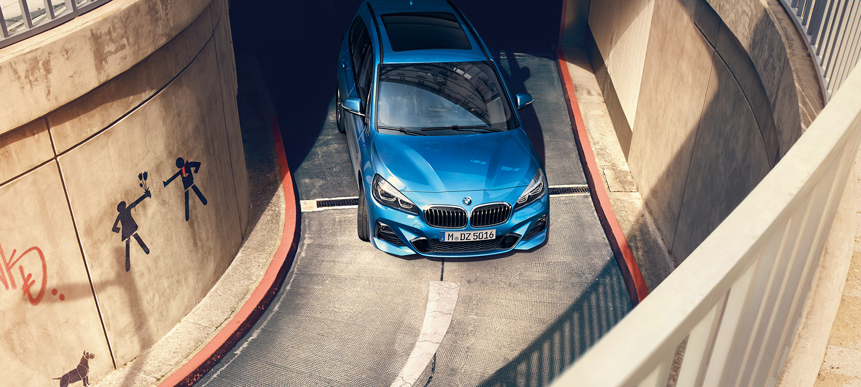 BMW serii 2 Gran Tourer podczas jazdy na parkingu wielopoziomowym BMW serii 2 Gran Tourer F46, niebieski Estoril, metalizowany, widok z góry podczas jazdy na parkingu wielopoziomowym