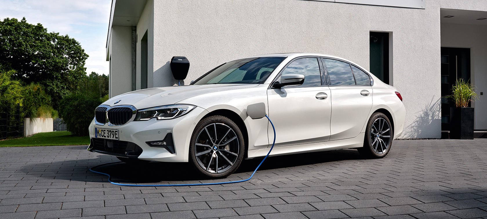Hybryda plug-in BMW serii 3 Limuzyna 2021 G20 G20, półprofil podczas ładowania Hybryda plug-in BMW serii 3 Limuzyna 2021 G20, półprofil podczas ładowania przed garażem