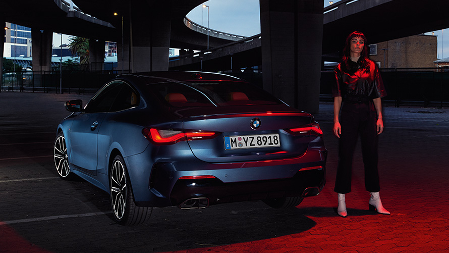 BMW 4 Series Coupé (G22), Artic Race Blue metallic, rear view with person BMW serii 4 Coupé (G22), niebieski Arctic Race, metalizowany, widok z tyłu z osobą