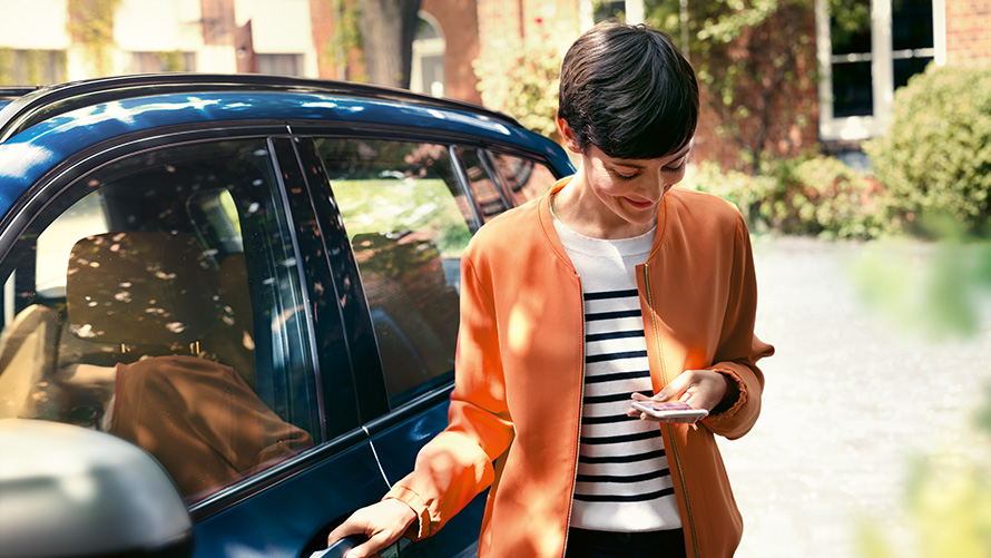 Serwis BMW kobieta ze smartfonem w ręku przed swoim BMW Serwis BMW kobieta ze smartfonem w ręku przed swoim BMW
