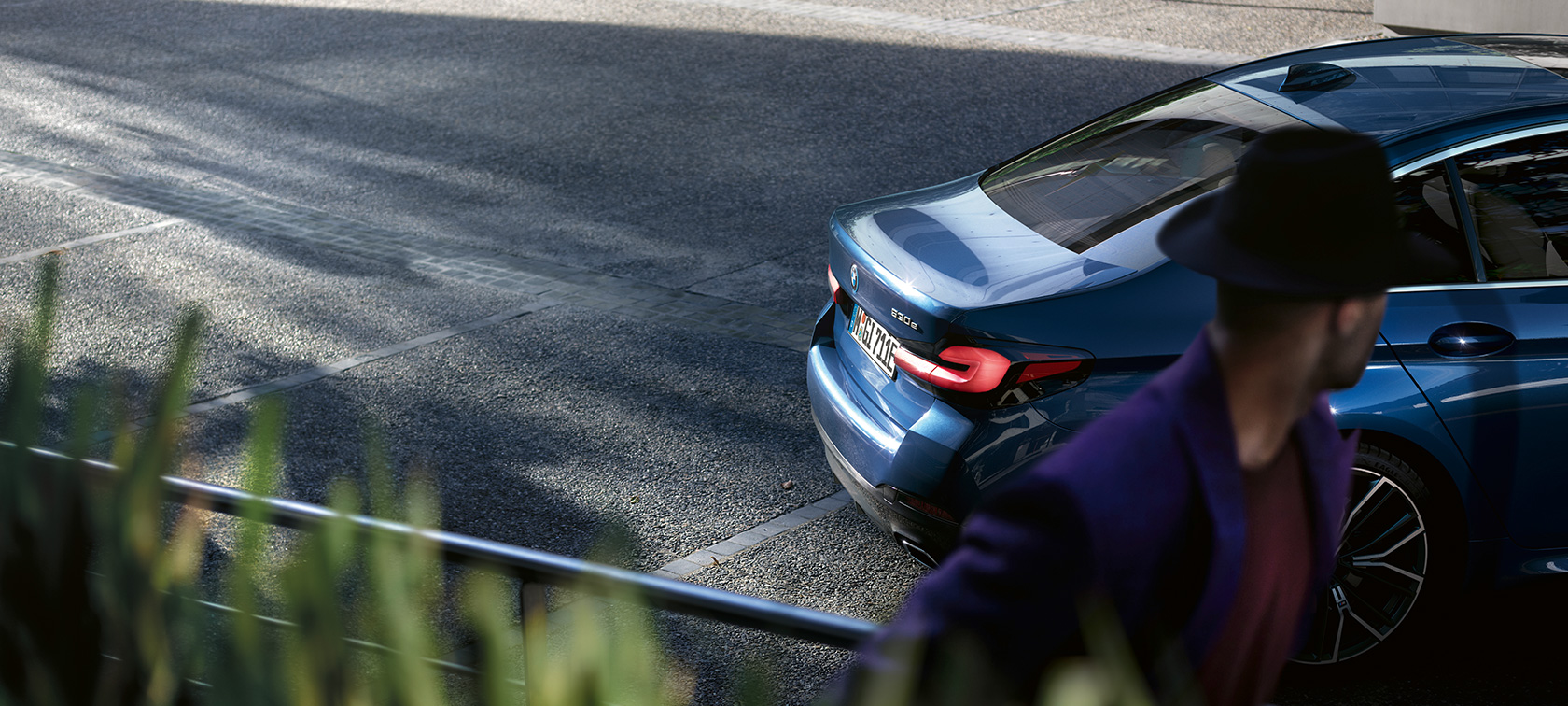 Mężczyzna stojący za zaparkowanym BMW serii 5 Limuzyna G30 BMW serii 5 Limuzyna G30, modernizacja 2020, mężczyzna stojący za zaparkowanym BMW