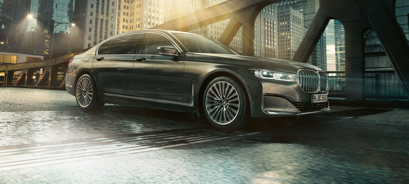 BMW serii 7 Limuzyna, profil BMW serii 7 Limuzyna z profilu z otwartymi drzwiami przed oświetlonym hotelem