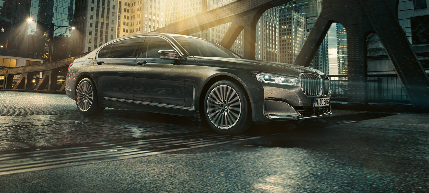 BMW serii 7 Limuzyna, profil BMW serii 7 Limuzyna z profilu z otwartymi drzwiami przed oświetlonym hotelem