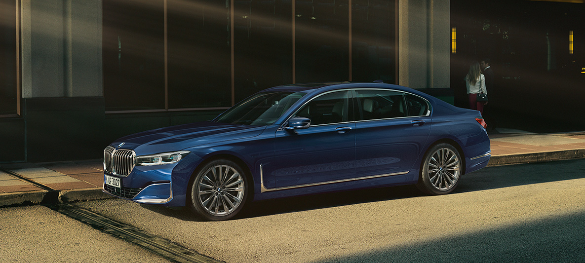 BMW Individual serii 7 Limuzyna, profil Czerwone BMW Individual serii 7 Limuzyna z profilu w miejskiej scenerii