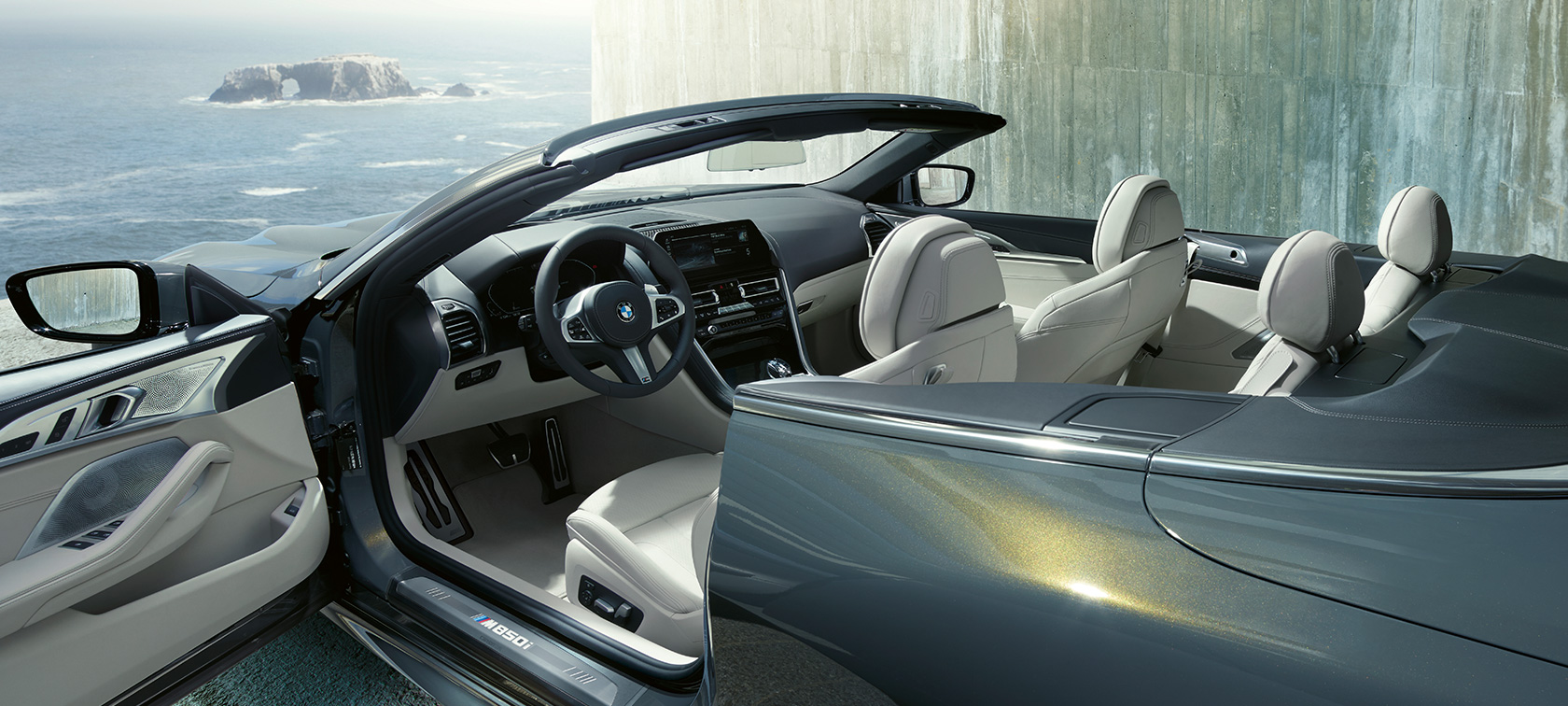 BMW M850i xDrive, szary drawit metalizowany, widok z boku, miękki dach i otwarte drzwi. BMW M850i xDrive, szary drawit metalizowany, widok z boku, miękki dach i otwarte drzwi.