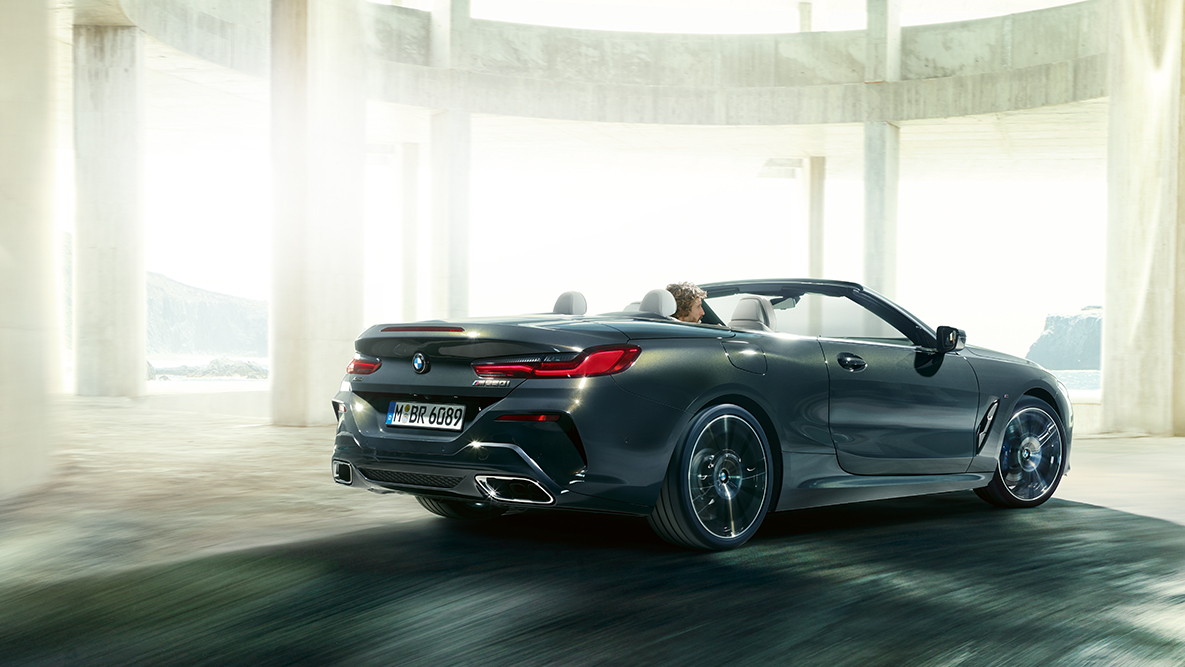 BMW M850i xDrive z otwartym dachem, w ruchu, widok z boku. BMW M850i xDrive z otwartym dachem, w ruchu, widok z boku.