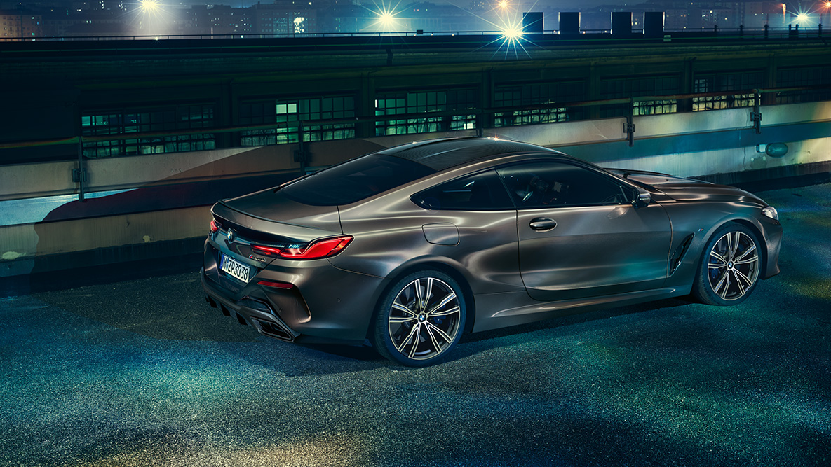 Zdjęcie boku BMW serii 8 Coupé podczas postoju. Zdjęcie boku BMW serii 8 Coupé z wyposażeniem BMW Individual podczas postoju w nocnej miejskiej scenerii.