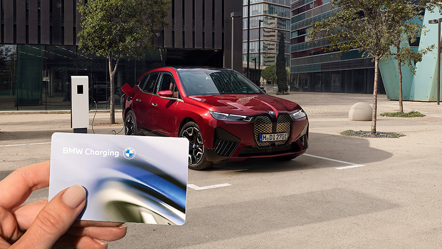 BMW iX i20 elektryczny SUV BMW iX xDrive50, ładowanie BMW iX i20 2021 elektryczny SUV BMW iX xDrive50 czerwony awenturyn ładowanie z publicznej stacji szybkiego ładowania