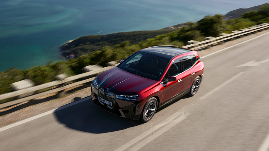 BMW iX i20 elektryczny SUV BMW iX xDrive50 osiągi BMW iX i20 2021 elektryczny SUV BMW iX xDrive50 czerwony awenturyn podczas jazdy na drodze osiągi