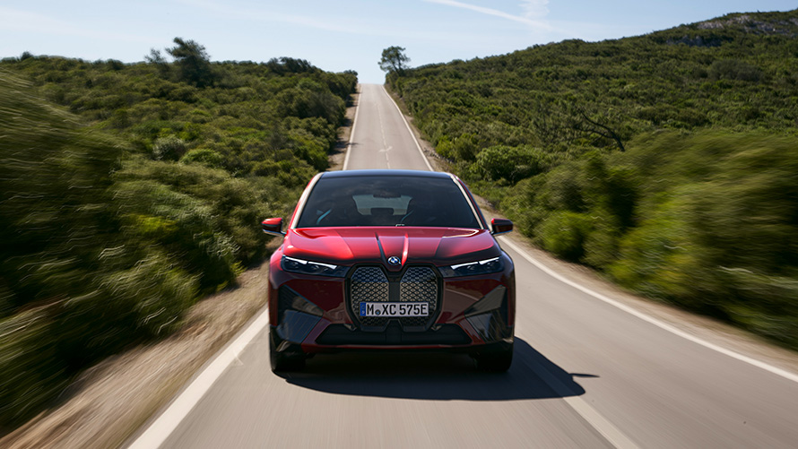 BMW iX i20 elektryczny SUV BMW iX xDrive50 zasięg BMW iX i20 2021 elektryczny SUV BMW iX xDrive50 czerwony awenturyn podczas jazdy na drodze zasięg