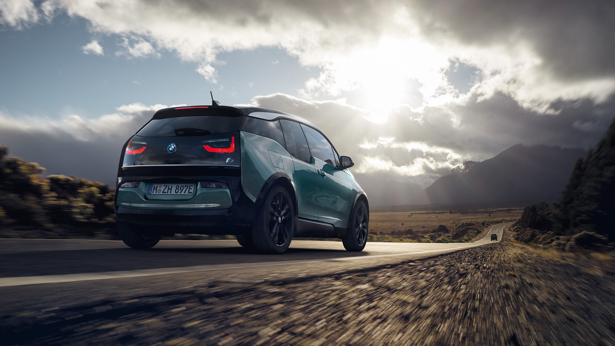 BMW i3 2018, beż Jucaro, tylny półprofil podczas jazdy poza miastem BMW i3 I01 2018, beż Jucaro z akcentami w metalizowanym kolorze mroźnym szarym, tylny półprofil podczas jazdy poza miastem
