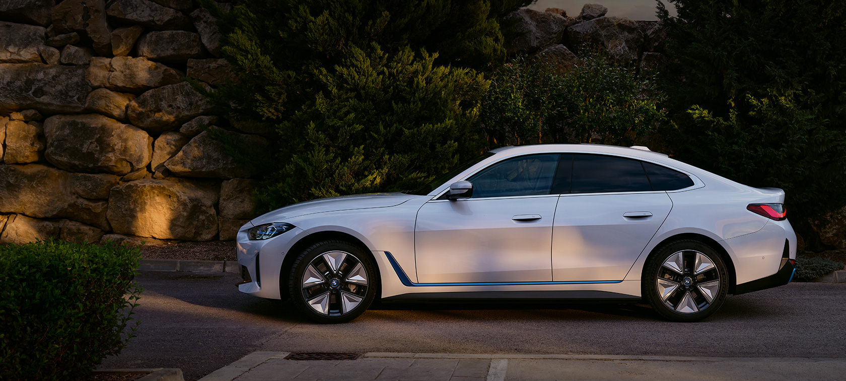 BMW i4 eDrive40 G26 2021 biel mineralna przedni półprofil podczas postoju na tle jeziora i wzgórza