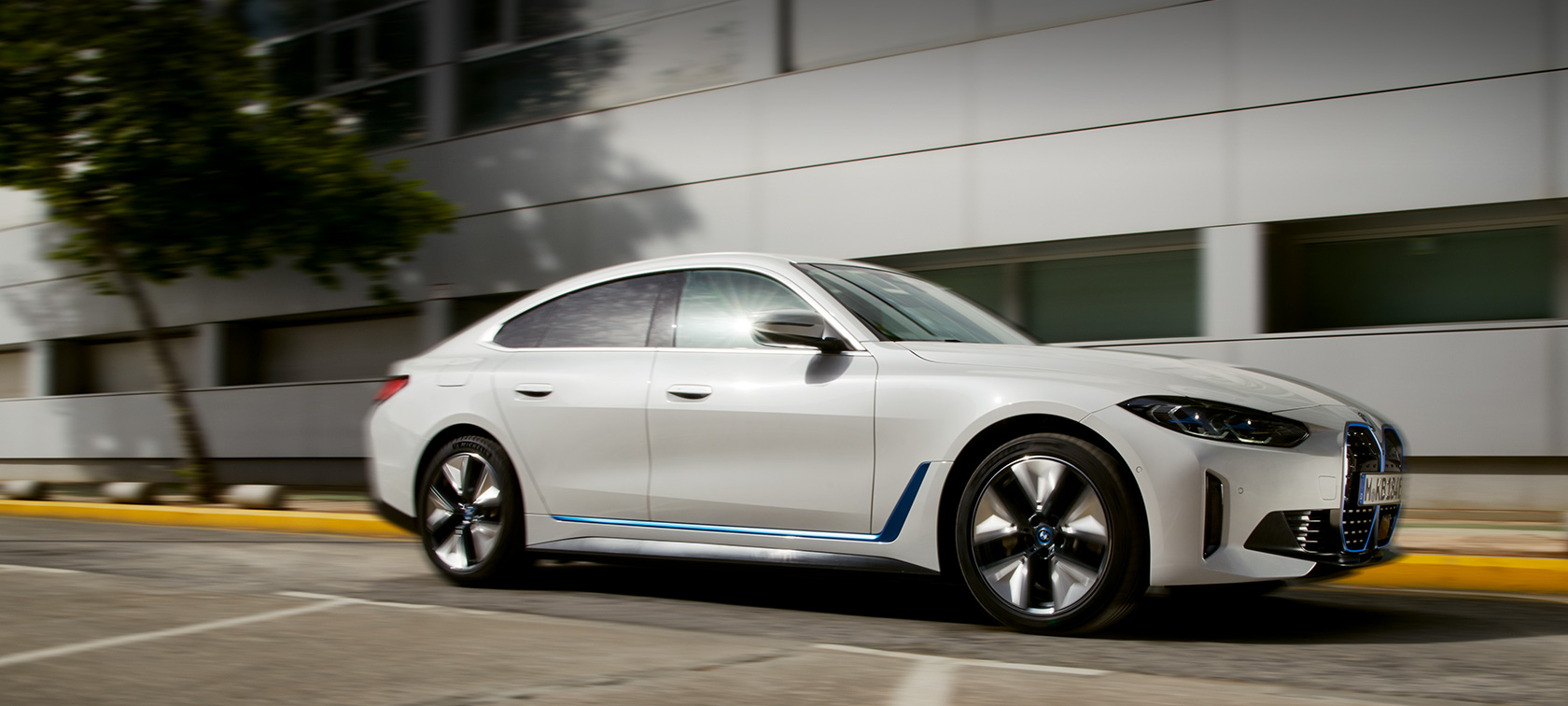 BMW i4 eDrive40 G26 2021 półprofil podczas jazdy na tle budynku BMW i4 eDrive40 G26 2021 półprofil podczas jazdy na tle budynku