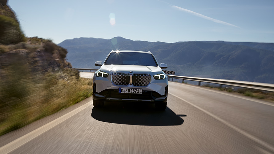 BMW iX1 U11 2022 BEV widok z przodu BMW iX1 U11 BEV 2022 biel mineralna metalizowany widok z przodu podczas jazdy górską drogą