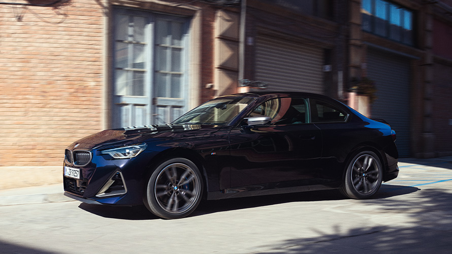 Półprofil BMW M240i xDrive Coupé G42 2021 BMW serii 2 Coupé G42 2021 Thundernight metalizowany półprofil podczas postoju przed halą magazynową