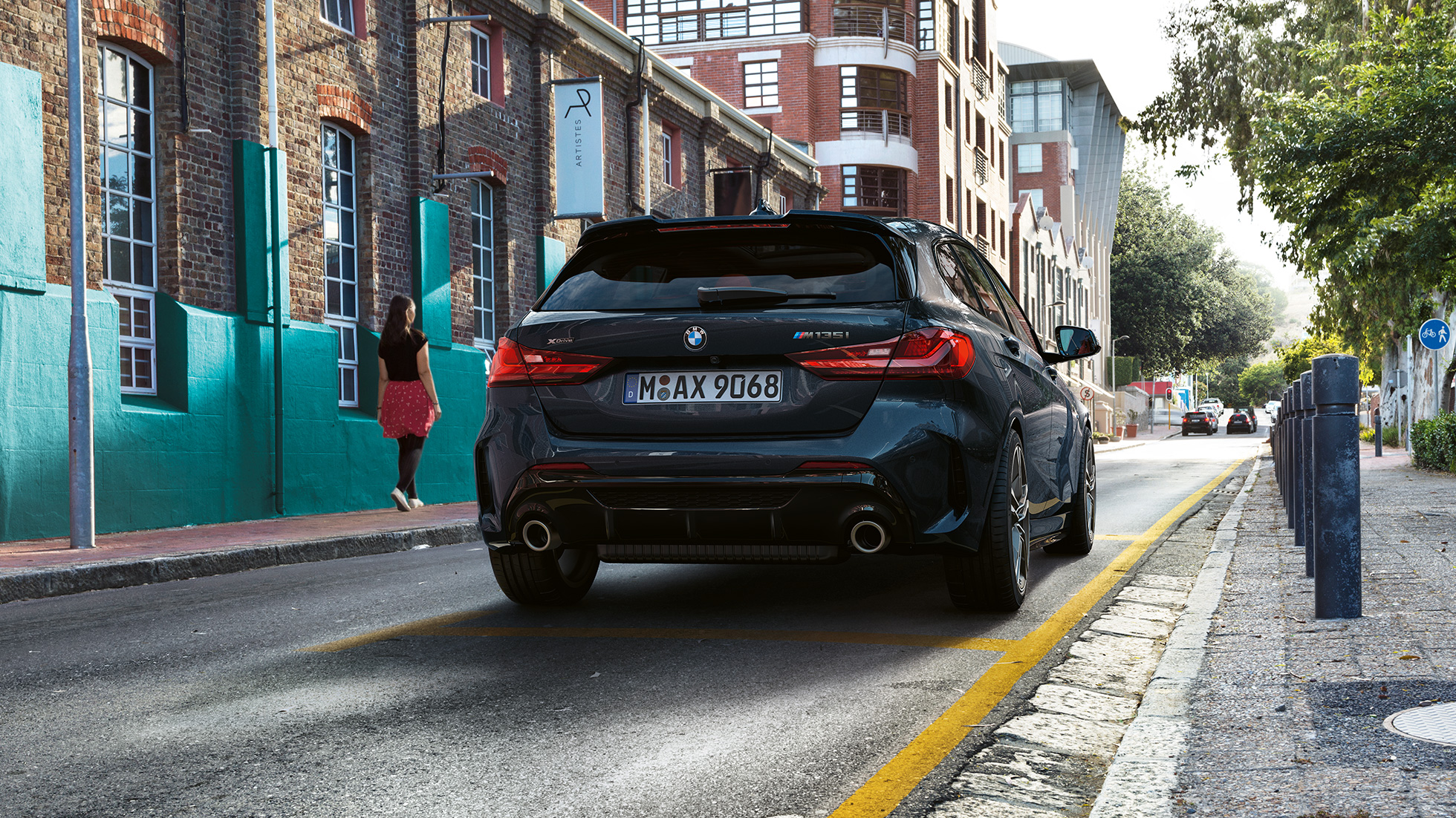 BMW M135i xDrive, widok z tyłu. Nowe BMW M135i xDrive w metalizowanym kolorze szafirowoczarnym, widok z tyłu, samochód zaparkowany.