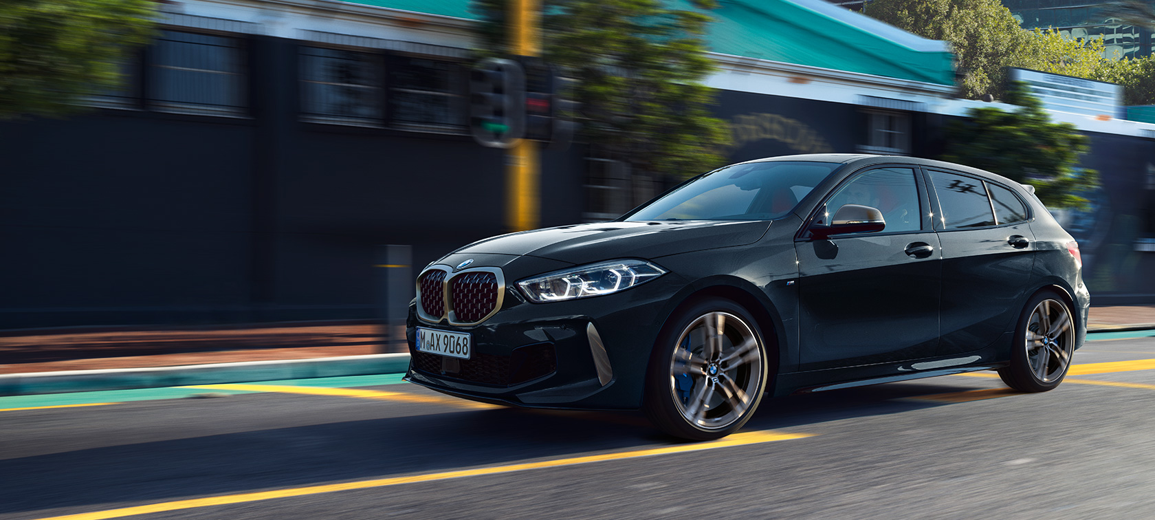 Nowe BMW M135i xDrive. Nowe BMW M135i xDrive w metalizowanym kolorze szafirowoczarnym, półprofil z boku podczas jazdy.