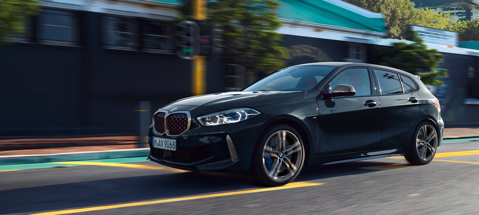 BMW serii 1 M135i xDrive (F40) w kolorze szafirowoczarnym metalizowanym samochód podczas jazdy w miejskiej scenerii