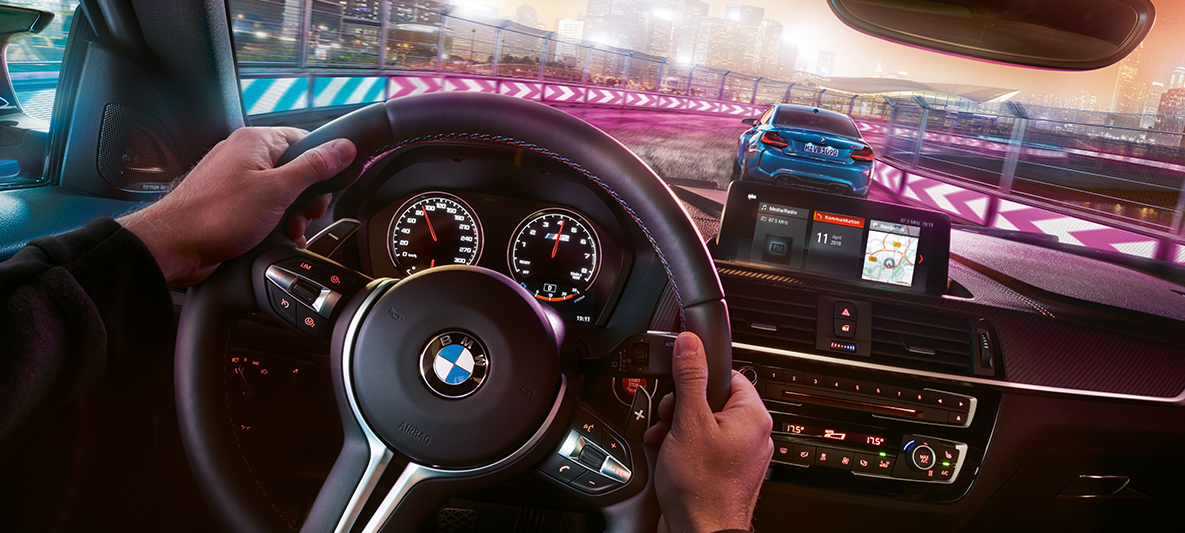 BMW M2 Competition sportowe fotele. Cockpit i sportowe fotele M w BMW M2 Competition z nocnym widokiem w tle.