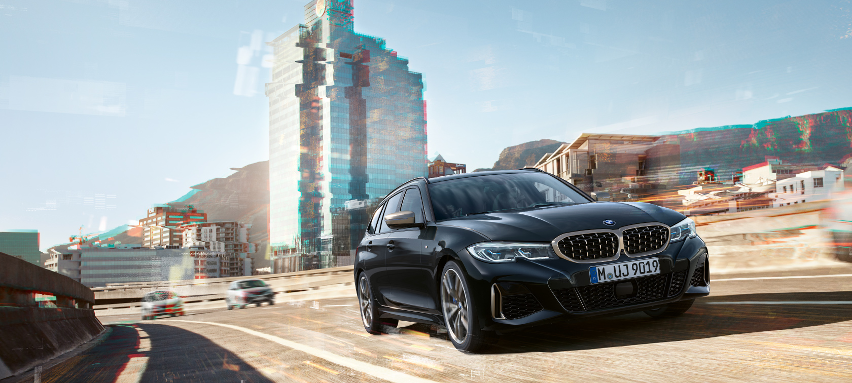 ujęcie dynamiczne z półprofilu na przód na miejskim tle BMW M340i xDrive Touring, ujęcie dynamiczne z półprofilu na przód na miejskim tle