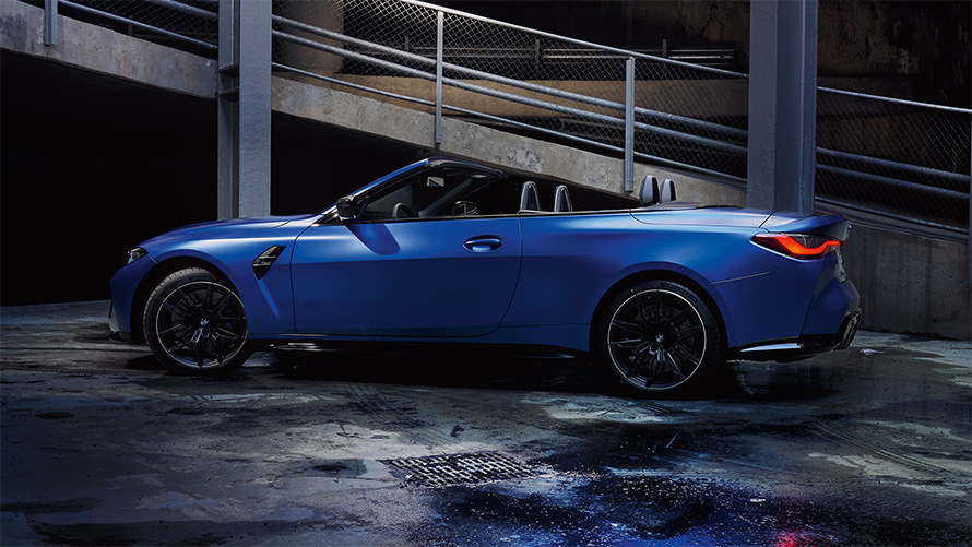 BMW M4 Cabrio Competition z M xDrive G83 2021 widok z boku przy otwartym dachu BMW M4 Cabrio Competition z M xDrive G83 2021 mroźny niebieski Portimao metalizowany widok z boku przy otwartym dachu