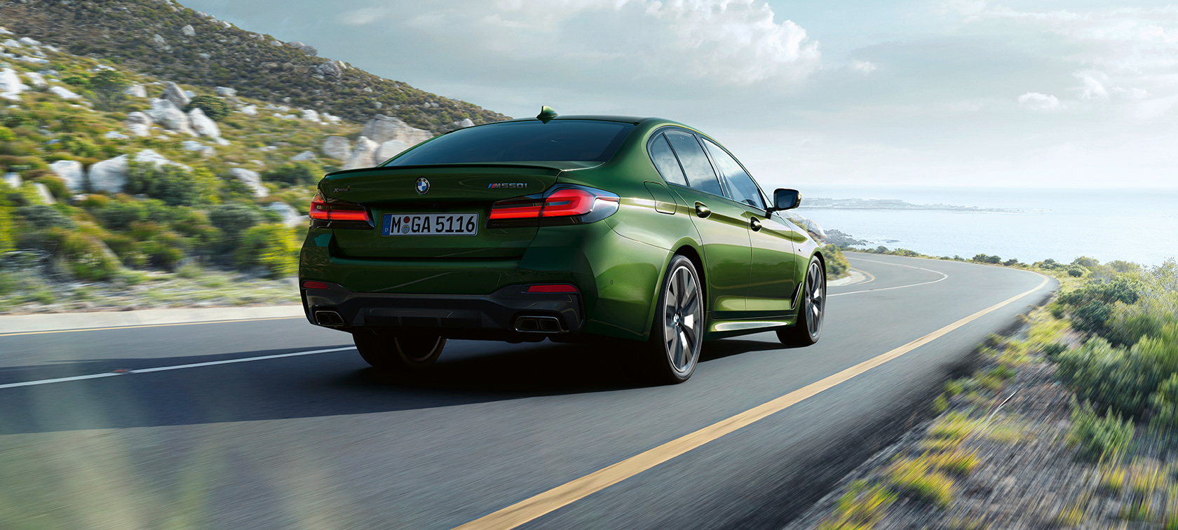 BMW M550i xDrive Limuzyna G30 LCI Facelift 2020, tylny półprofil podczas jazdy BMW M550i xDrive Limuzyna G30 LCI Facelift 2020 BMW Individual, Verde Ermes metalizowany, tylny półprofil podczas jazdy