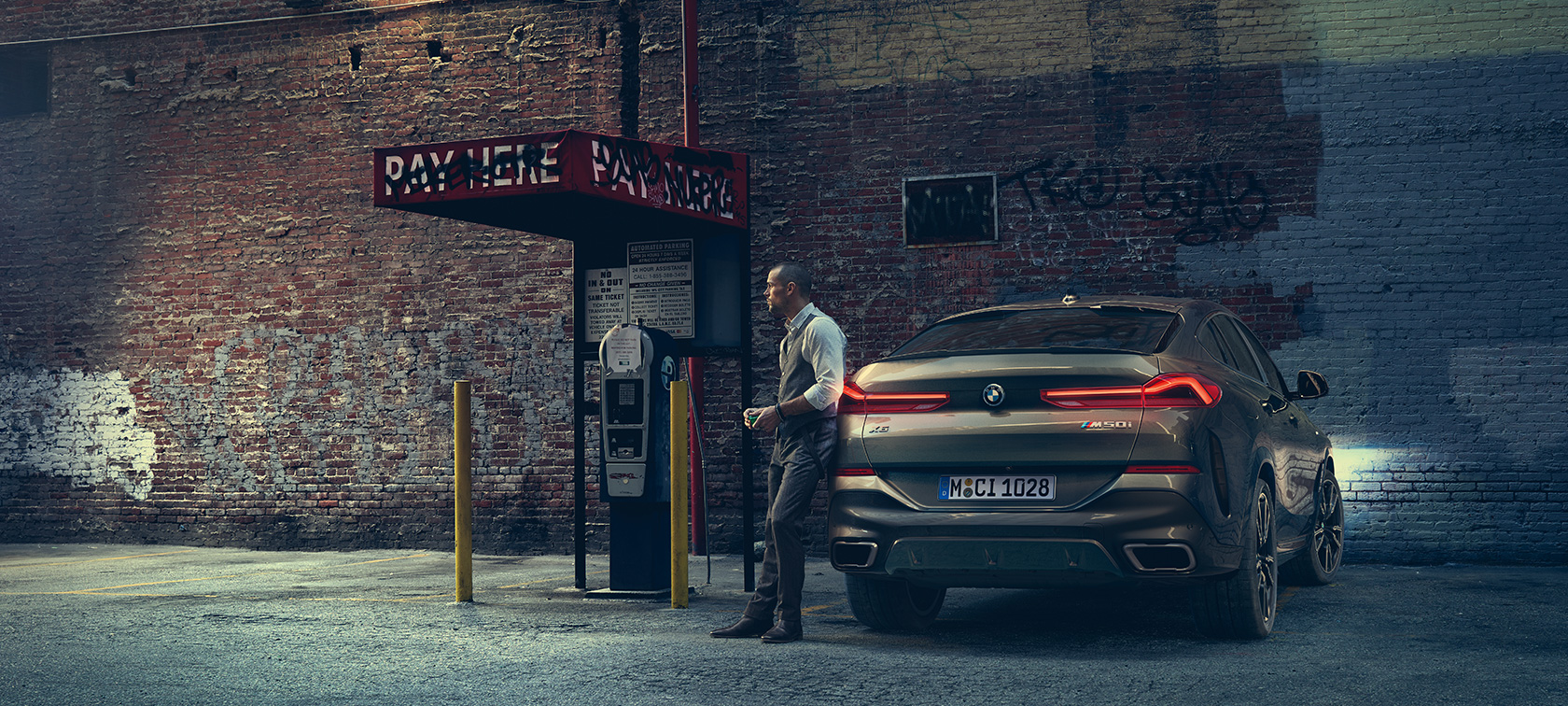 Tył BMW X6 M50i. Mężczyzna opierający się tył BMW X6 M50i.