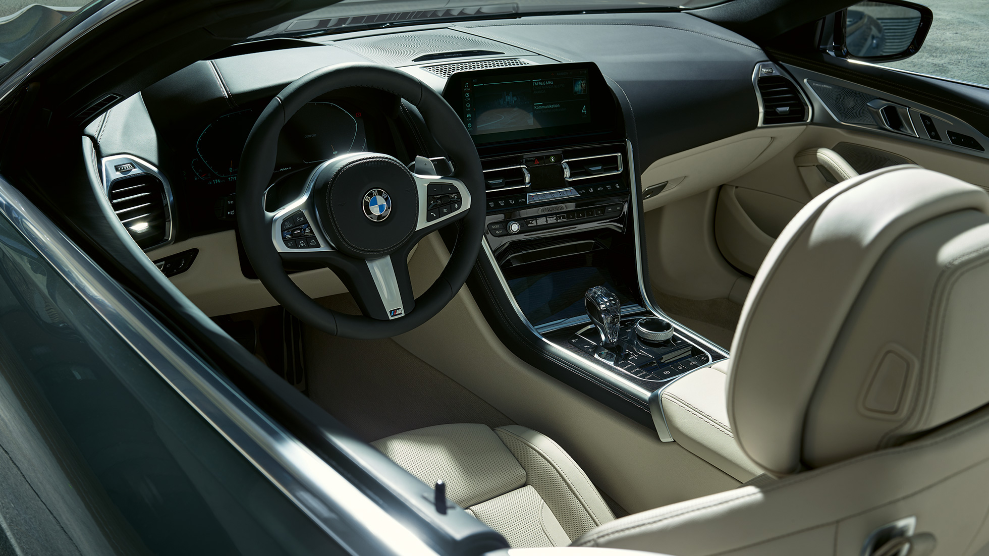 BMW M850i xDrive Cabrio, kokpit. BMW M850i xDrive Cabrio w metalizowanym kolorze szarego drawitu z otwartym dachem, kokpit z kierownicą sportową M.