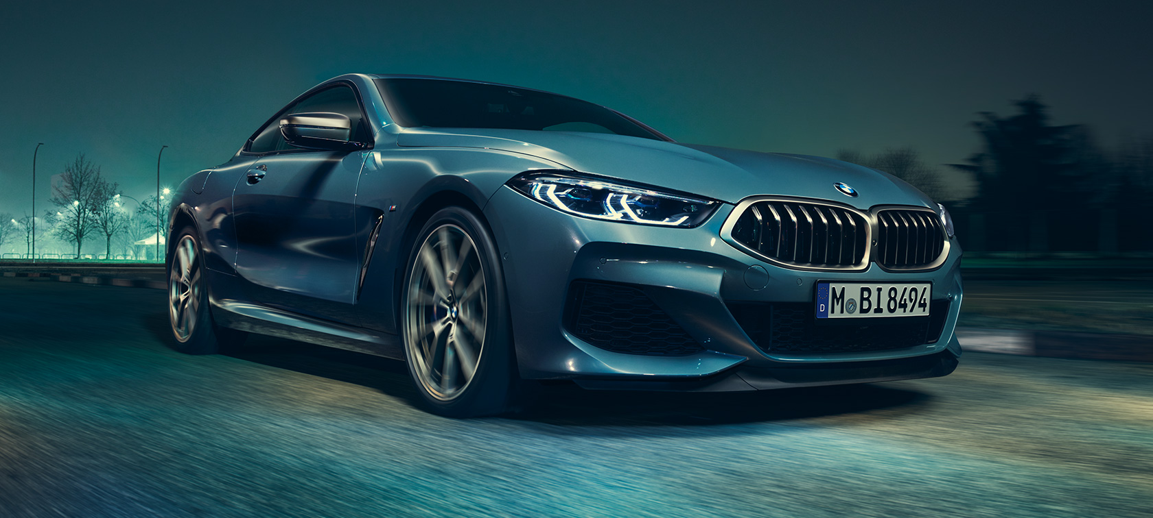 BMW M850i xDrive Coupé, przedni półprofil. BMW M850i xDrive Coupé w metalizowanym kolorze niebieskim Barcelona, przedni półprofil podczas jazdy.