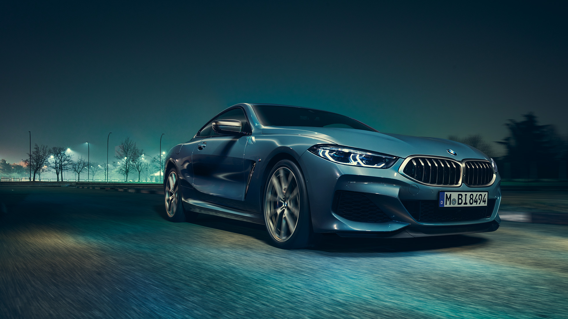 BMW M850i xDrive Coupé, lewy przedni półprofil. BMW M850i xDrive Coupé w metalizowanym kolorze niebieskim Barcelona, lewy przedni półprofil, jadące w nocy.