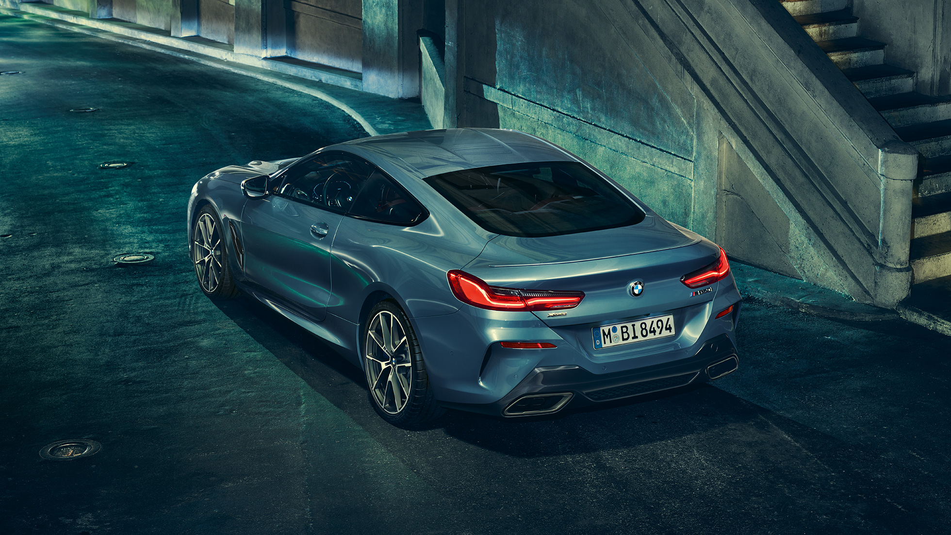 BMW M850i xDrive Coupé, lewy tylny półprofil. BMW M850i xDrive Coupé w metalizowanym kolorze niebieskim Barcelona, lewy tylny półprofil, stojące w nocy.