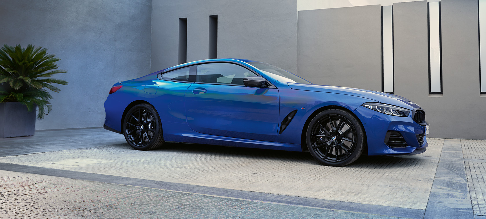 Widok z boku BMW M850i xDrive Coupé G15 LCI modernizacja 2022 BMW M850i xDrive Coupé G15 LCI modernizacja 2022 niebieski Portimao M metalizowany widok z boku podczas postoju na tle budynku